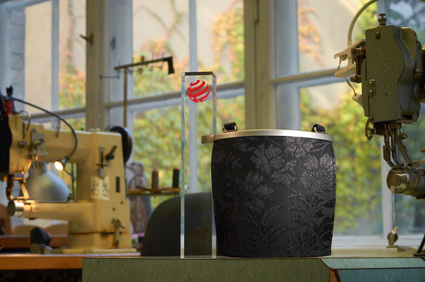 Olbrish handbag Arcade in horsehair stands next to a red dot best of the best prize and between two sewing machines