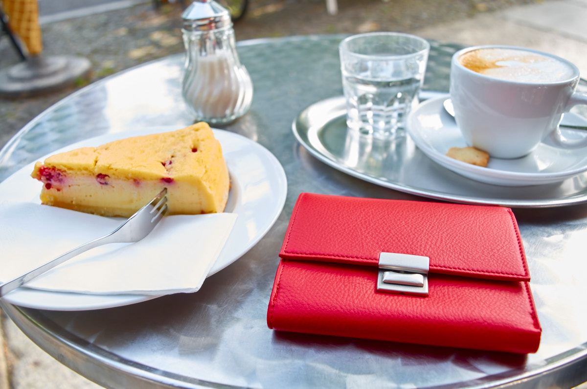 Olbrish wallet Monsieur Hulot in red nappa leather lays on coffee table with cappuccino and a slice of cake