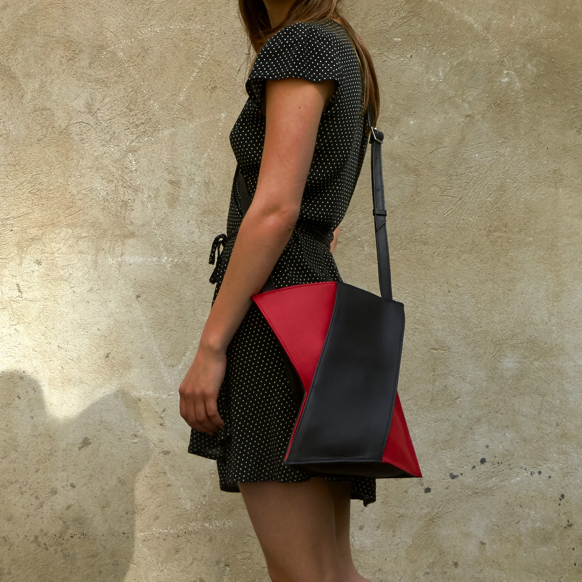 Frau trägt Olbrish Handtasche Generation X, Größe L, aus schwarz-rotem Nappaleder