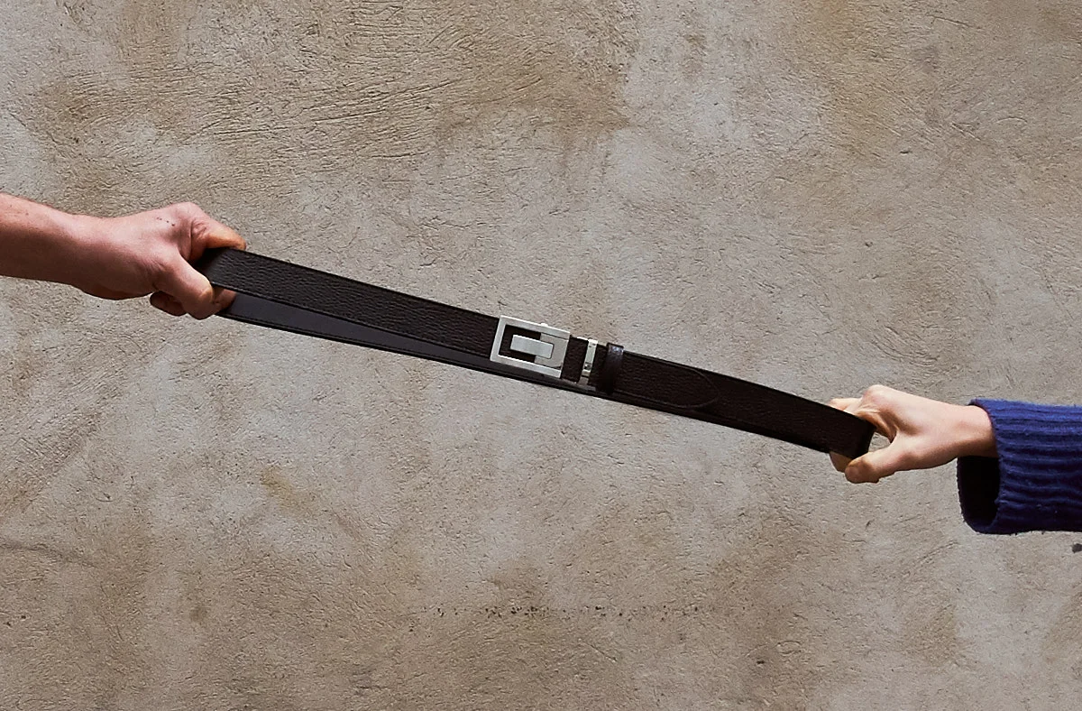 Detail view of two hands contemporary pulling at each side of an Olbrish belt