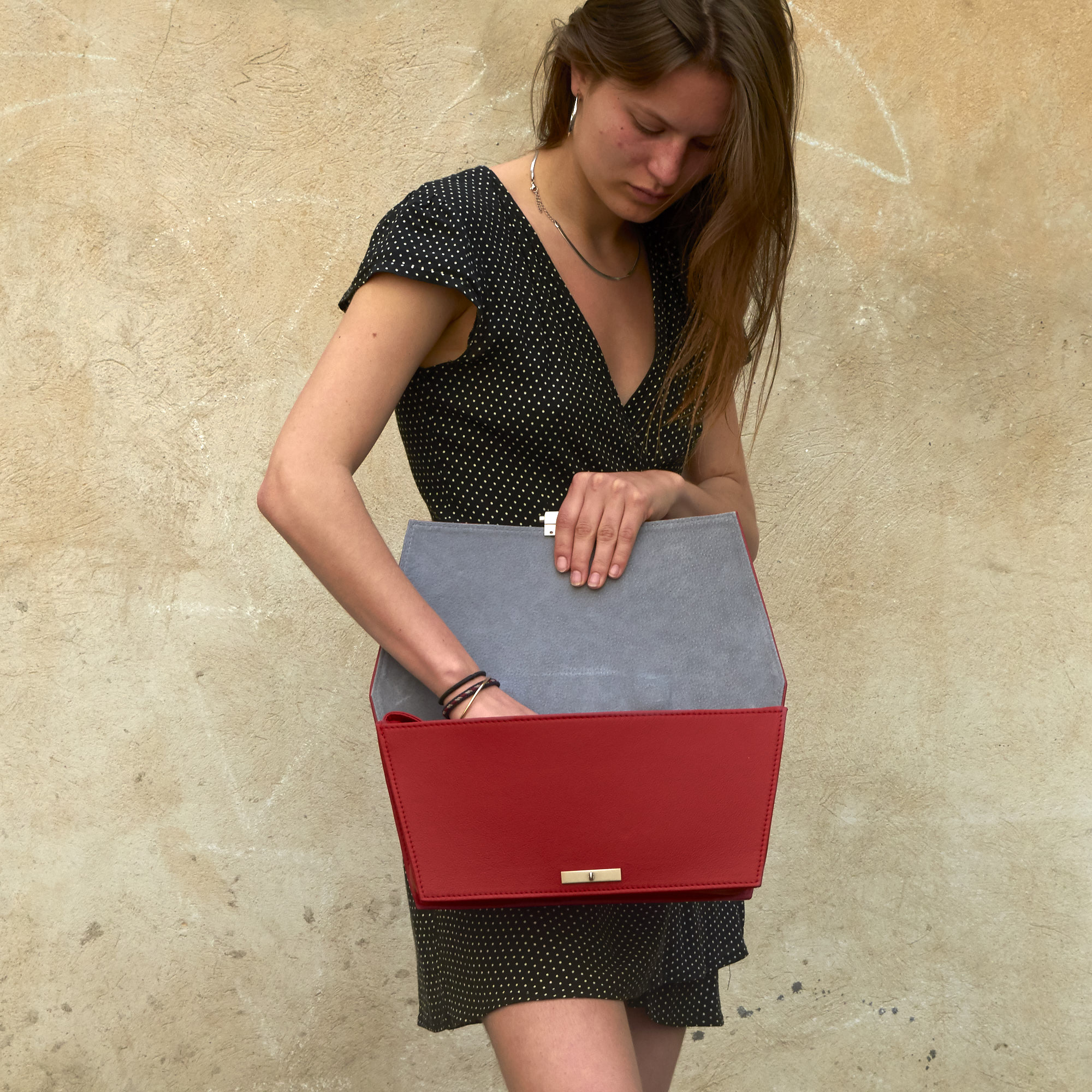 Frau schaut in Olbrish Handtasche Torii, Größe L, aus rotem Nappaleder