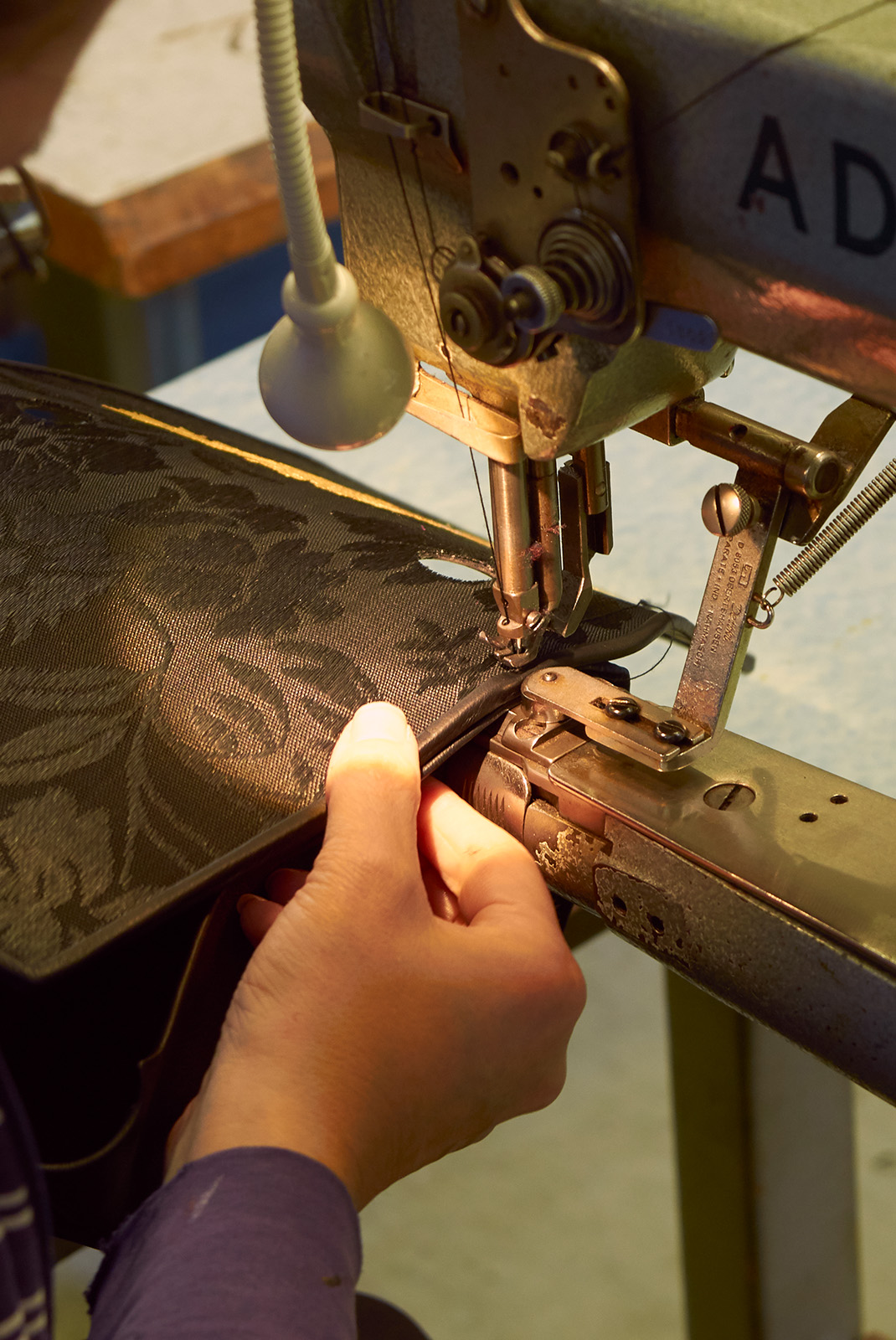 Woman stitching Olbrish horsehair handbag at a cylinder arm sewing machine