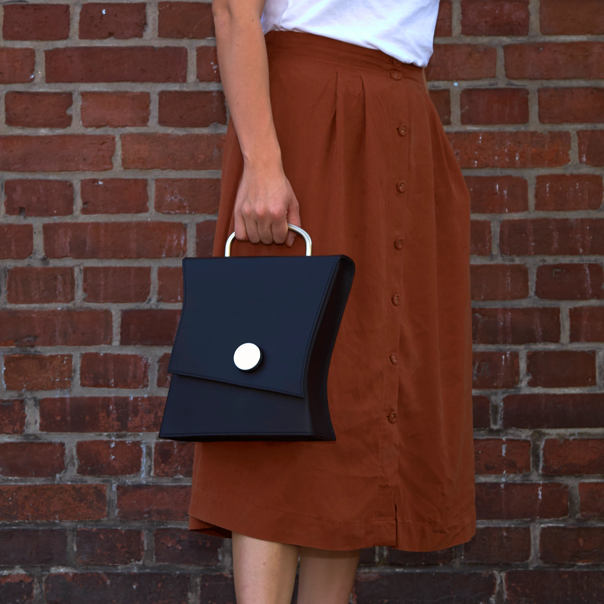 Frau trägt Olbrish Handtasche Swing, Nappaleder Schwarz, in der Hand