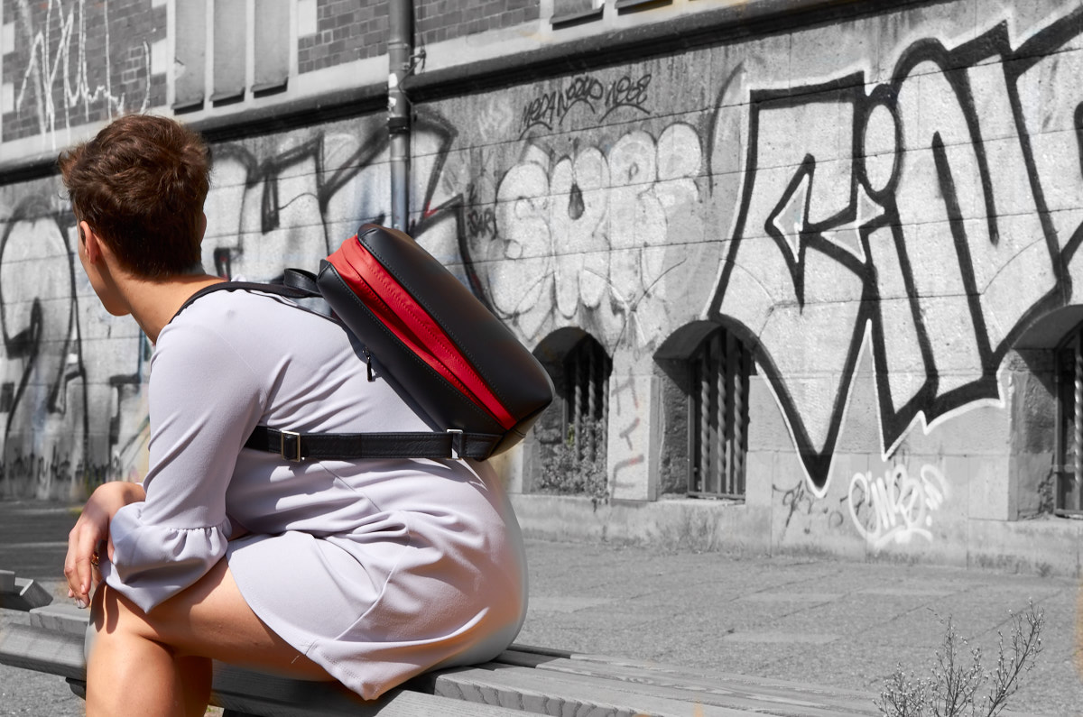 Woman sitting on a bench wearing Olbrish backpack Jetback in black and red nappa leather