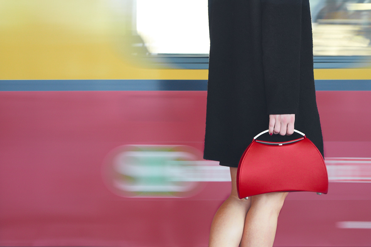 Olbrish Handtasche Teatime in rot, mit Modell, vor einfahrendem Zug